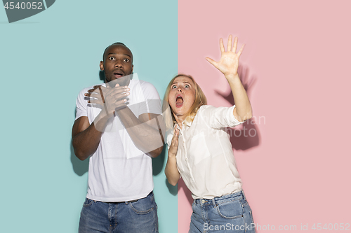 Image of Portrait of the scared couple on pink and blue studio background