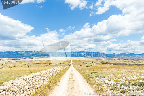 Image of Dirt road leading trough dry rocky Mediterranean coastal lanscape of Pag island, Croatia in summertime