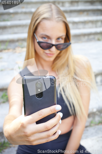 Image of Attractive young woman in sunglasses taking selfie.