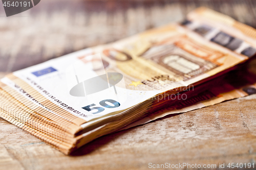 Image of Currency notes stacked on rustic wooden table background.