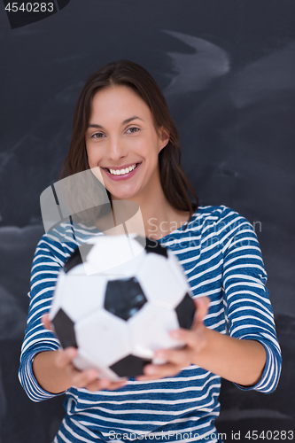 Image of woman holding a soccer ball in front of chalk drawing board