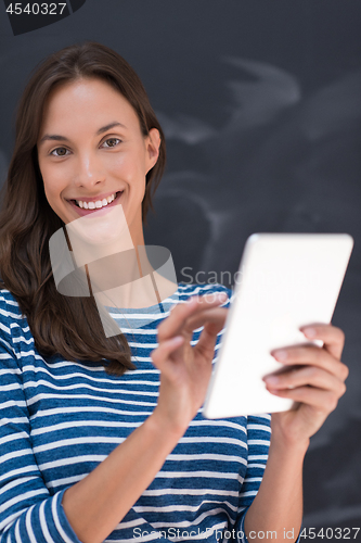 Image of woman using tablet  in front of chalk drawing board