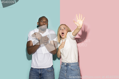 Image of Portrait of the scared couple on pink and blue studio background