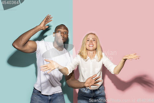 Image of The afro surprised couple watching sports match on tv at home, successful game. Different emotions concept. Studio shot with african american man and woman