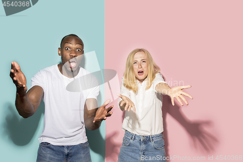 Image of The afro surprised couple watching sports match on tv at home, successful game. Different emotions concept. Studio shot with african american man and woman