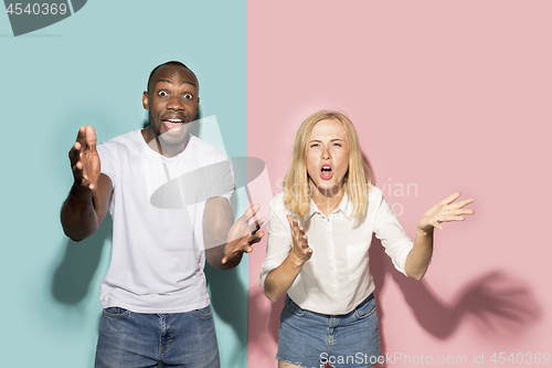 Image of The afro surprised couple watching sports match on tv at home, successful game. Different emotions concept. Studio shot with african american man and woman