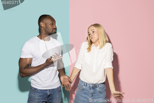 Image of Beautiful female and male portrait on pink and blue studio backgroud. The young emotional couple