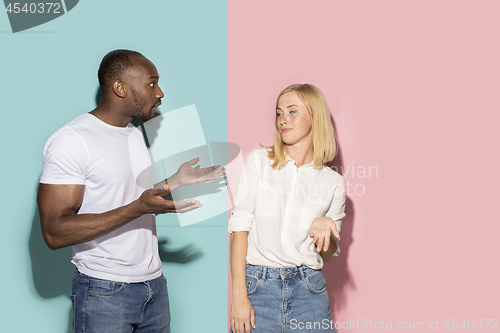 Image of Beautiful female and male portrait on pink and blue studio backgroud. The young emotional couple