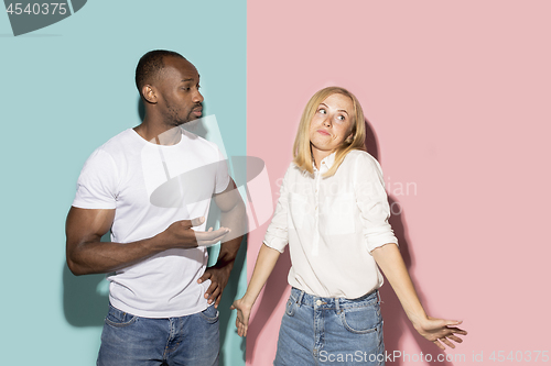 Image of Beautiful female and male portrait on pink and blue studio backgroud. The young emotional couple