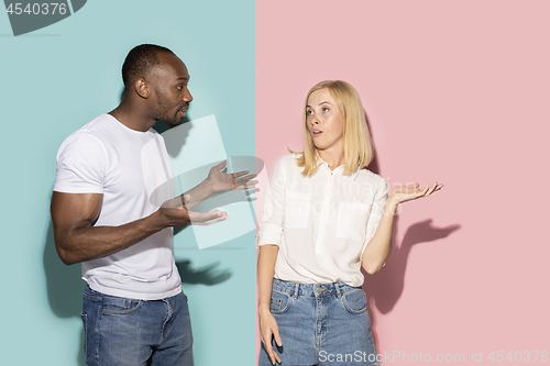 Image of Beautiful female and male portrait on pink and blue studio backgroud. The young emotional couple