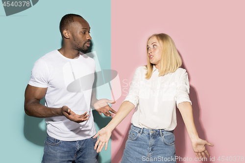 Image of Beautiful female and male portrait on pink and blue studio backgroud. The young emotional couple