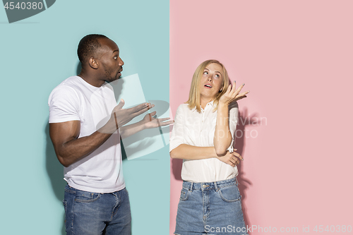 Image of Beautiful female and male portrait on pink and blue studio backgroud. The young emotional couple