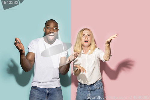 Image of The afro surprised couple watching sports match on tv at home, successful game. Different emotions concept. Studio shot with african american man and woman
