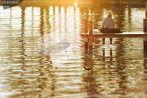 Image of a woman sitting on a wooden jetty at Starnberg Lake Tutzing Bava