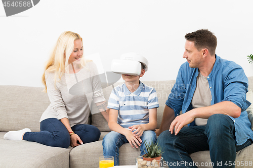 Image of Happy family at home on living room sofa having fun playing games using virtual reality headset