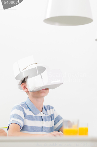 Image of Amazed child using virtual reality headsets while sitting at the dinner table.