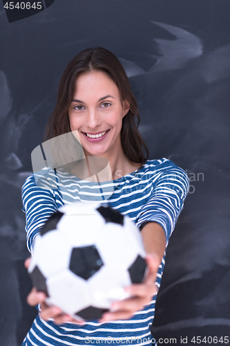 Image of woman holding a soccer ball in front of chalk drawing board