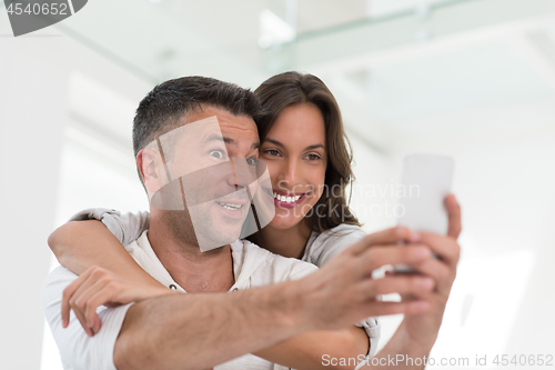 Image of happy couple using mobile phone at home