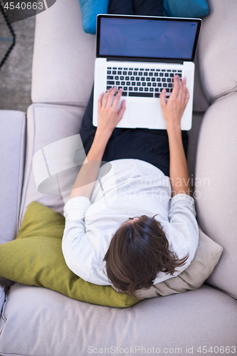 Image of Young woman using laptop at home top view