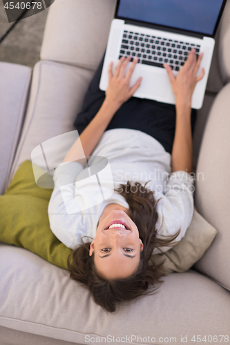 Image of Young woman using laptop at home top view