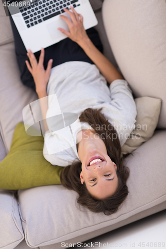 Image of Young woman using laptop at home top view