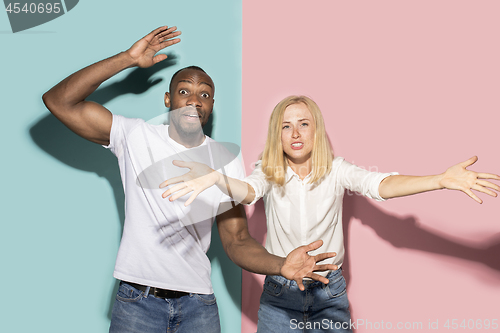 Image of The afro surprised couple watching sports match on tv at home, successful game. Different emotions concept. Studio shot with african american man and woman