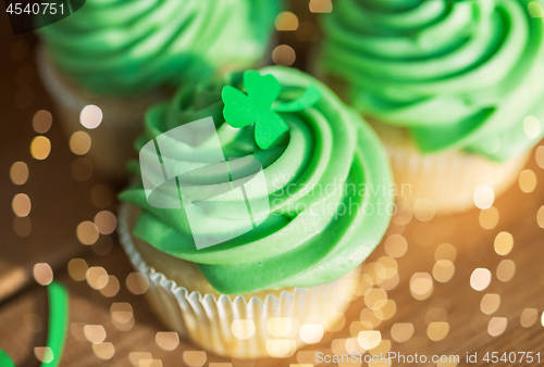 Image of green cupcakes and shamrock on wooden table