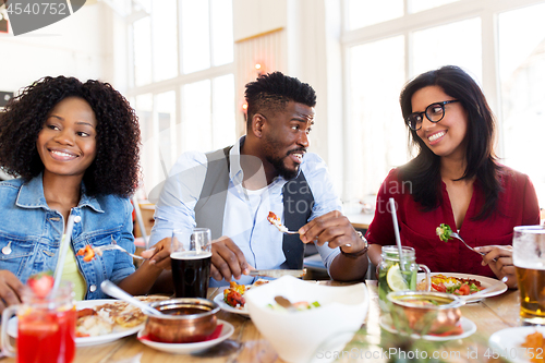 Image of happy friends eating and talking at restaurant