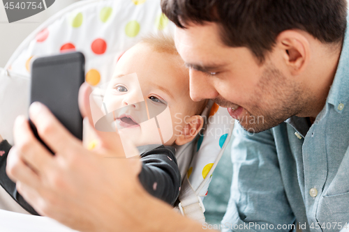 Image of father with baby daughter taking selfie at home