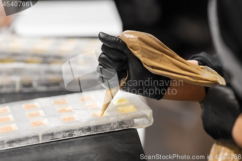 Image of confectioner filling mold by cream at pastry shop