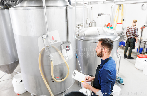 Image of man with clipboard at craft brewery or beer plant