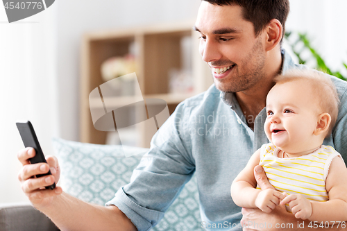 Image of father with baby daughter using smartphone at home