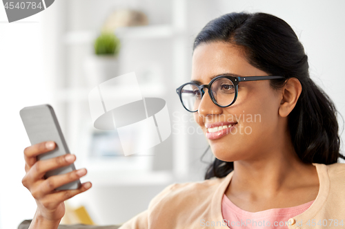 Image of happy indian woman using smartphone at home