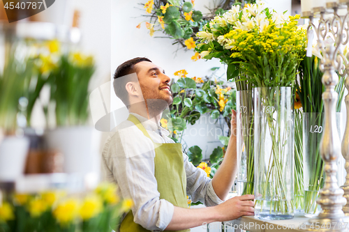 Image of happy florist man setting flowers at flower shop