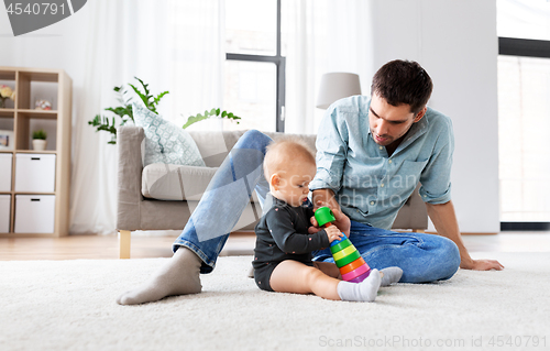 Image of father playing with little baby daughter at home