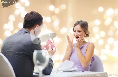 Image of man showing woman present in red box at restaurant