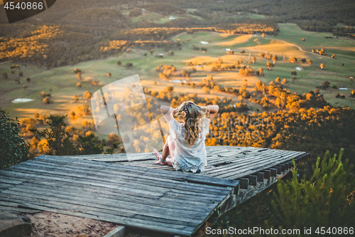 Image of Woman watching the sunset over the mountain valley