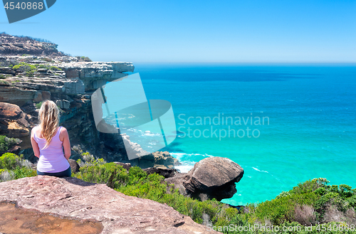 Image of Female sitting on cliffs by the ocean