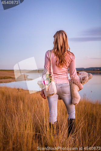 Image of Woman standing in long dry grasses by lake