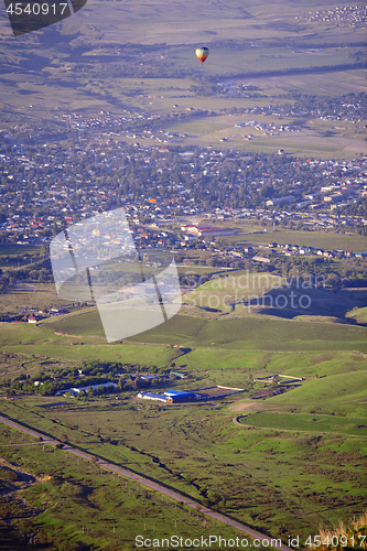 Image of Hot air balloon above the green field and villages