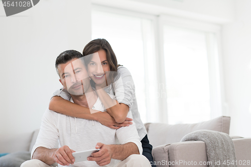 Image of happy couple using mobile phone at home