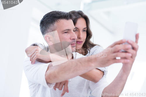 Image of happy couple using mobile phone at home