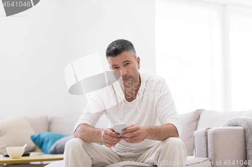 Image of young man using a mobile phone  at home