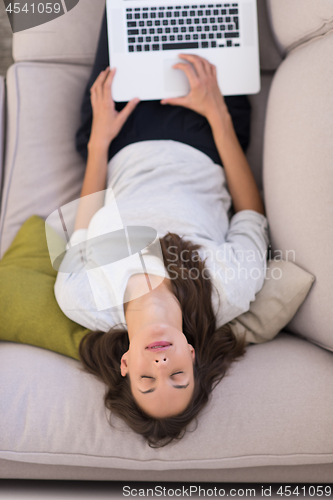 Image of Young woman using laptop at home top view