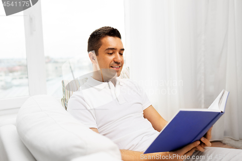 Image of happy man reading book at home