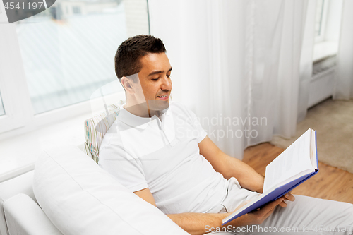 Image of happy man reading book at home