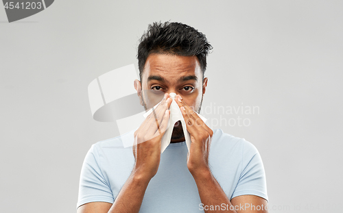 Image of indian man with paper napkin blowing nose