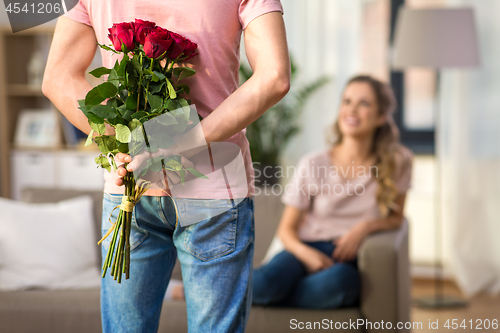 Image of woman and man with bunch of roses behind his back