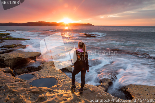 Image of Sunflare kissing the shoulder of a woman watching sunrise by the