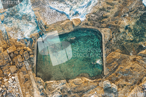 Image of Swimmers refresh themselves in coastal rock pool early morning.